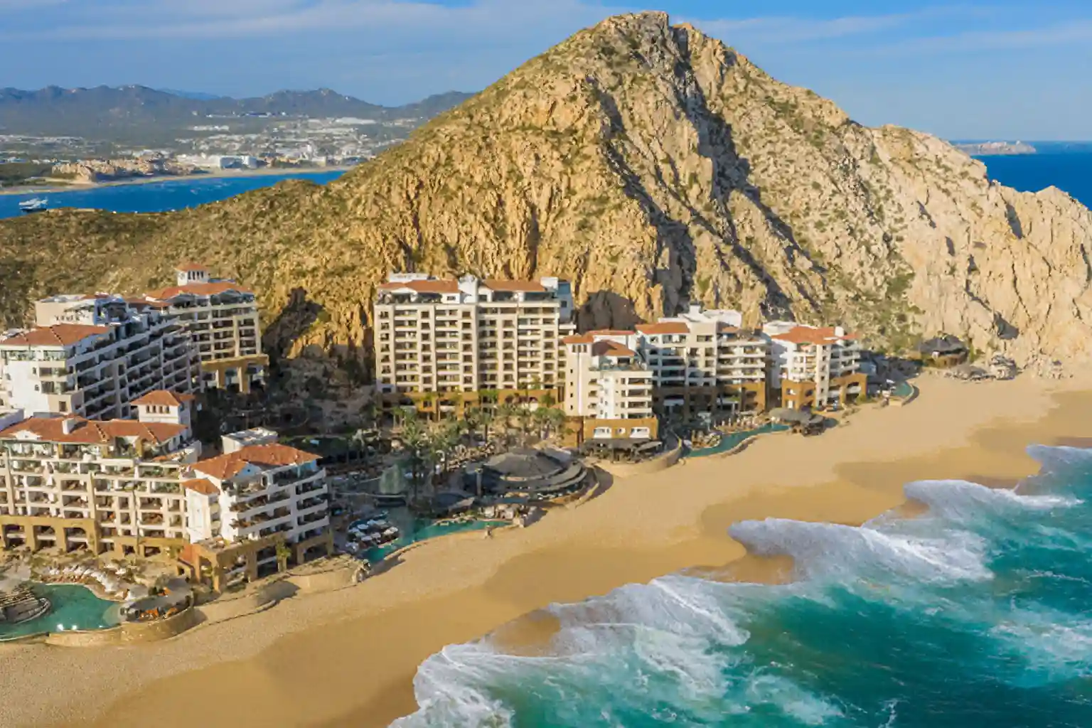 Resort frente al mar con vista a un acantilado y playa dorada en un destino costero de lujo.